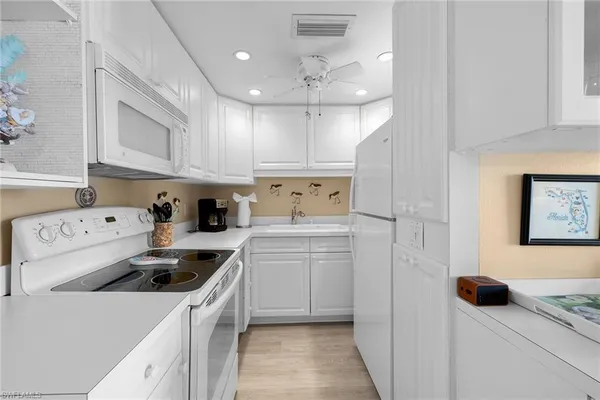 a kitchen with kitchen island white cabinets and white appliances