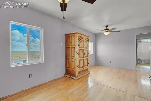 an empty room with windows and fan