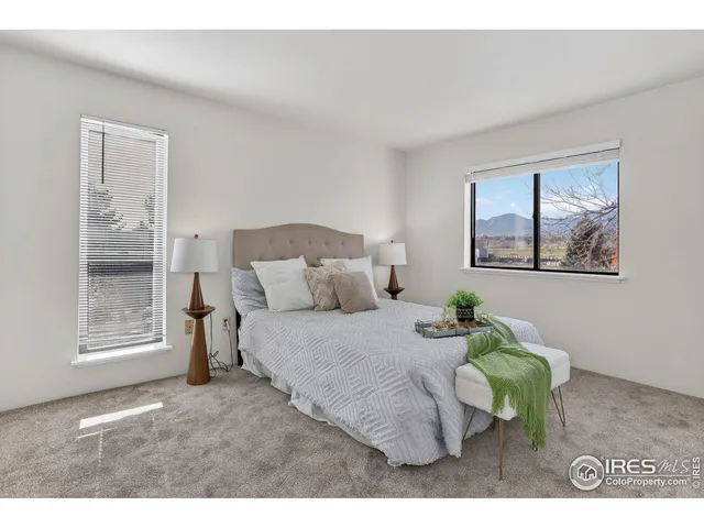 a bedroom with a bed mirror and painting on the wall