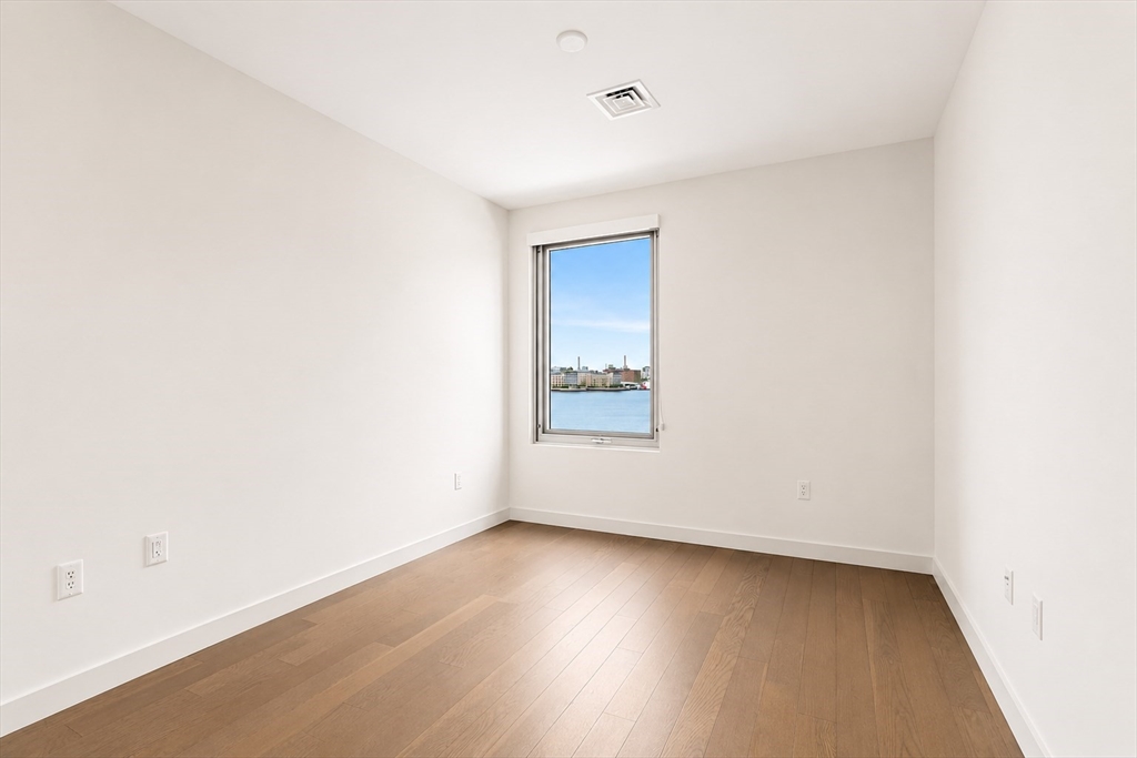 45 Lewis Street, Unit 312 Boston, MA 02128 - Photo 9 of 17 an empty room with wooden floor and windows