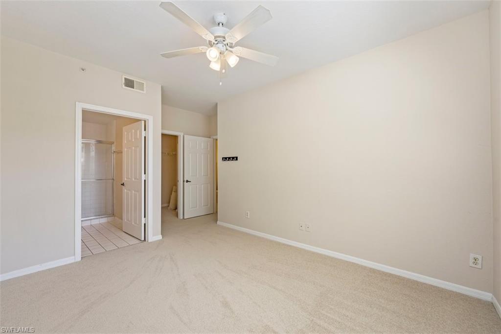 4635 St Croix Lane, Unit 1218 Naples, FL 34109 - Photo 16 of 40 Unfurnished bedroom featuring light colored carpet, a spacious closet, a closet, ceiling fan, and ensuite bathroom