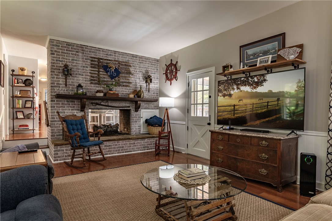 620 Seminole Point Road Fair Play, SC 29643 - Photo 24 of 50 A classic brick fireplace anchors this warm living space finished with hardwood flooring and leading to screened porch