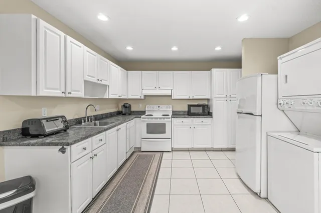 a kitchen with granite countertop a white stove top oven and white cabinets