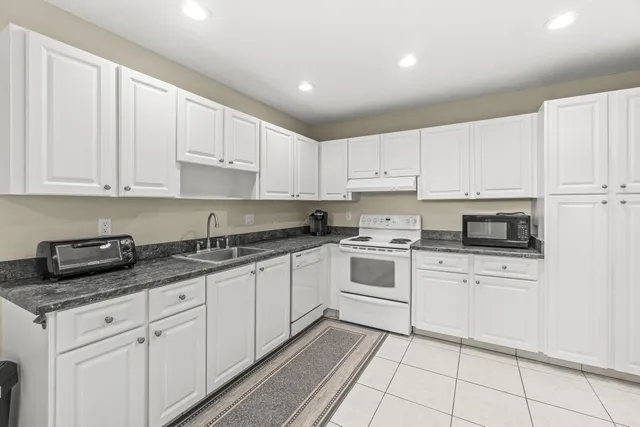 a kitchen with granite countertop white cabinets and white appliances
