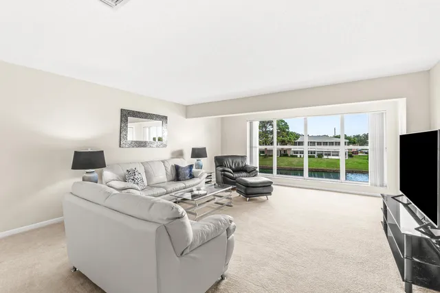 a living room with furniture large windows and flat screen tv