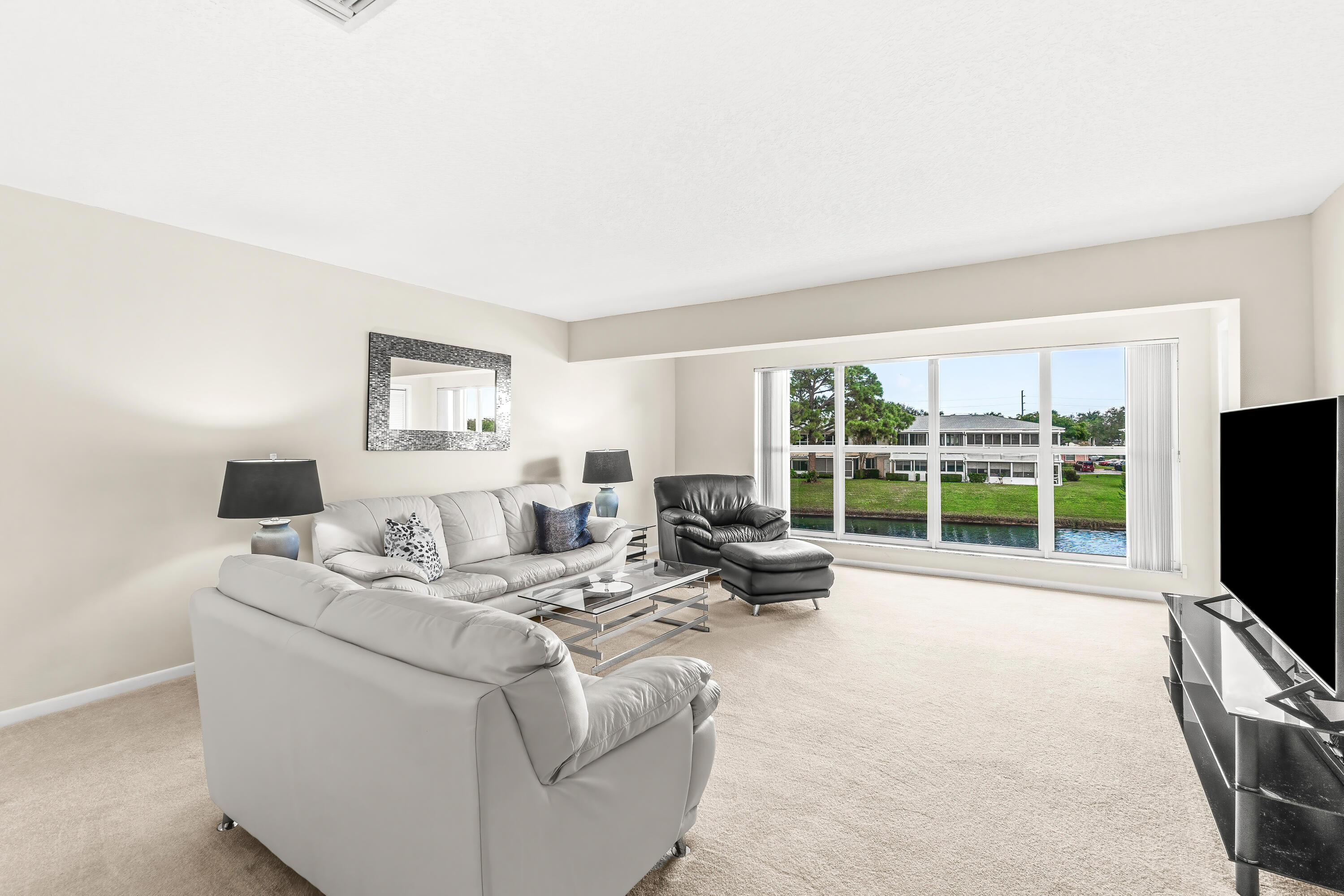 1521 Northwest 19th Terrace, Unit 202 Delray Beach, FL 33445 - Photo 3 of 32 a living room with furniture large windows and flat screen tv