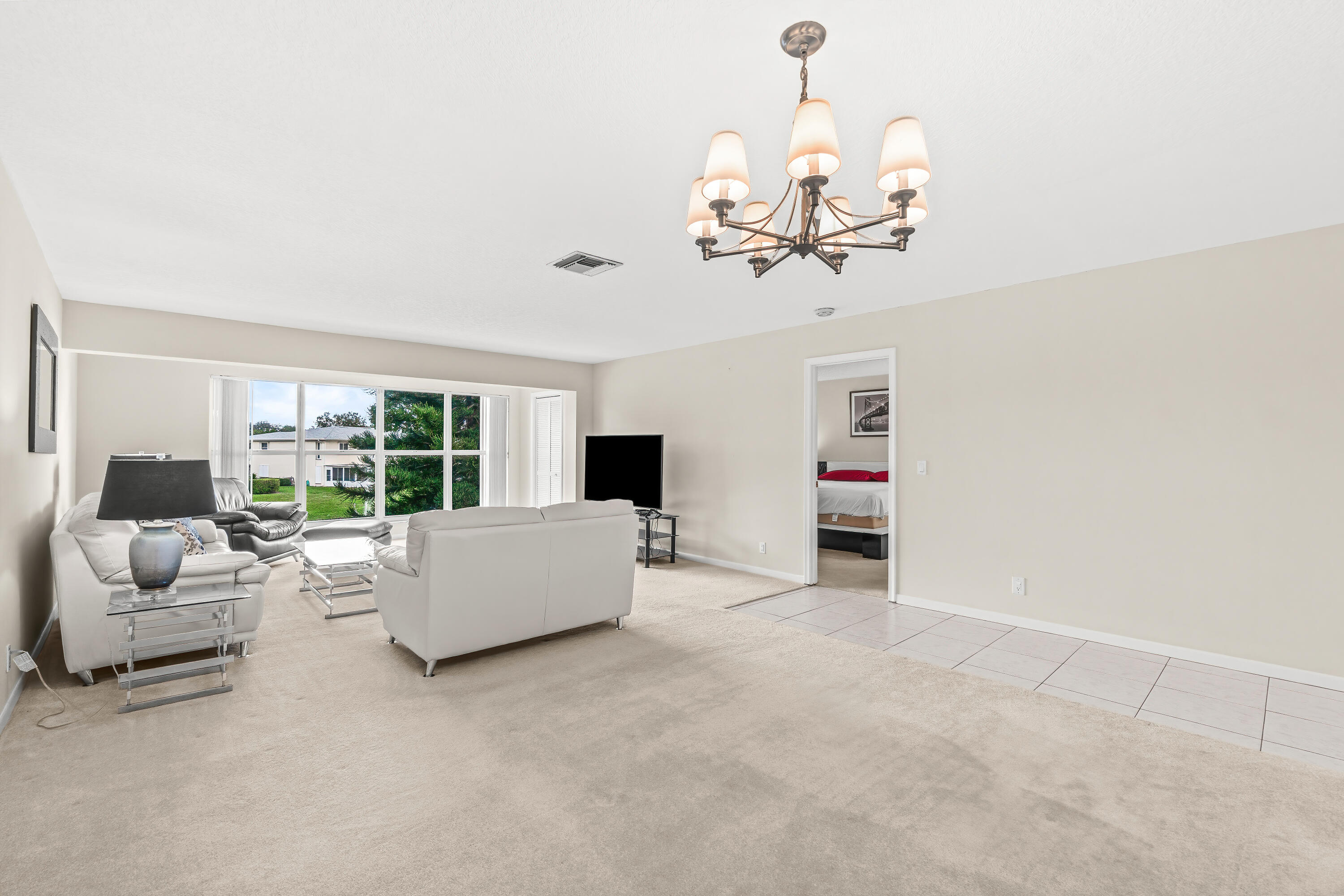 1521 Northwest 19th Terrace, Unit 202 Delray Beach, FL 33445 - Photo 8 of 32 a living room with furniture chandelier and a flat screen tv