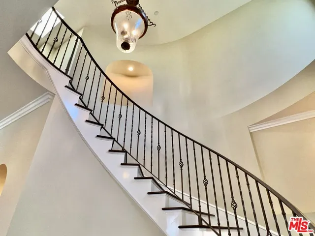 a view of staircase with railing and a chandelier