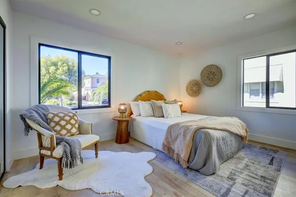 a bedroom with a large bed a potted plant and a window