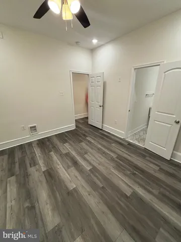 an empty room with a ceiling fan and wooden floor