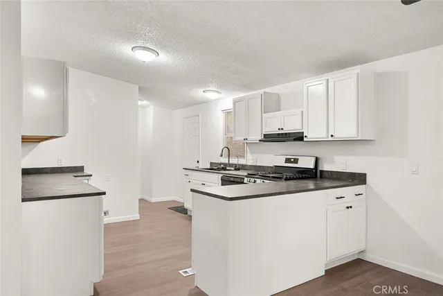 a kitchen with granite countertop white cabinets and black appliances