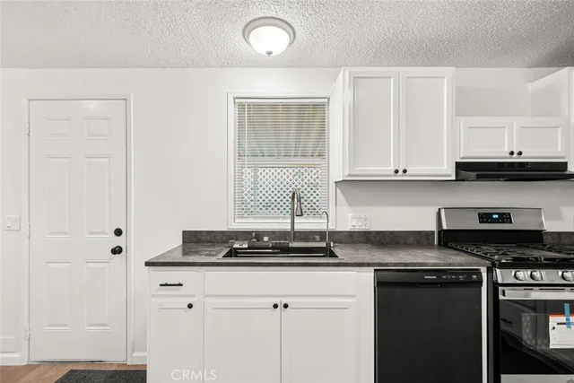 a kitchen with granite countertop a stove sink and cabinets