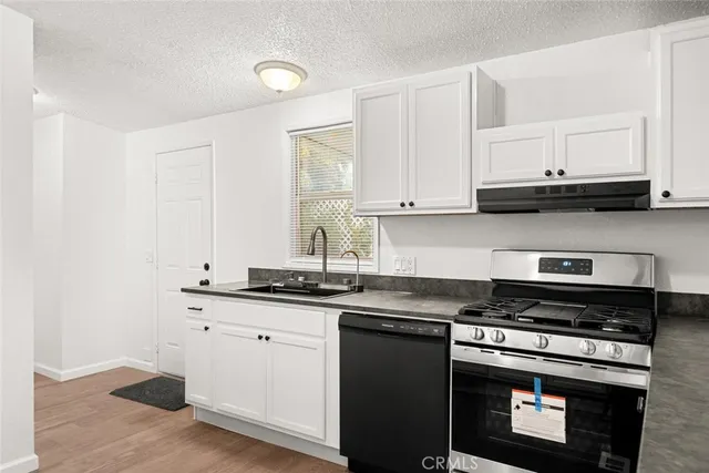 a kitchen with granite countertop white cabinets and black appliances