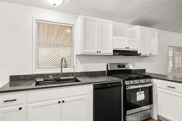 a kitchen with granite countertop a sink stainless steel appliances and white cabinets