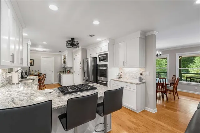 a large kitchen with granite countertop a stove a sink a dining table and chairs