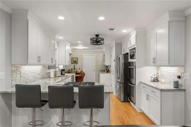 a kitchen with stainless steel appliances kitchen island granite countertop a refrigerator a stove a sink dishwasher with a dining table and chairs