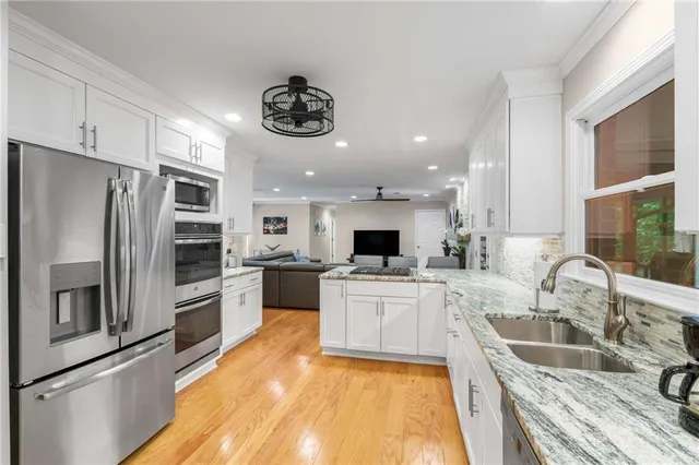 a large kitchen with a large counter top stainless steel appliances and cabinets
