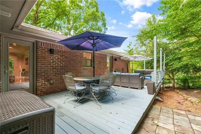 a view of a patio with table and chairs under an umbrella with a barbeque