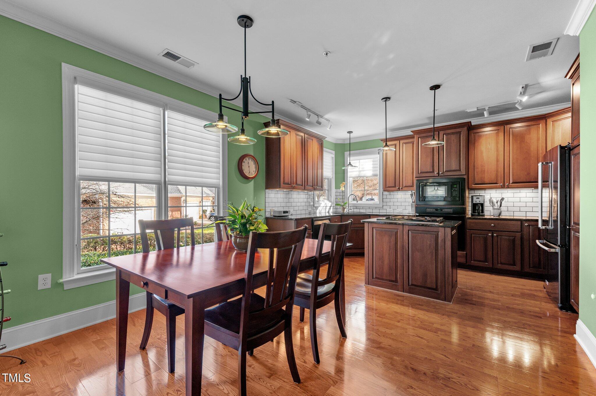 3700 Baron Cooper Pass, Unit 202 Raleigh, NC 27612 - Photo 21 of 49 a kitchen with stainless steel appliances granite countertop wooden floor dining table and chairs