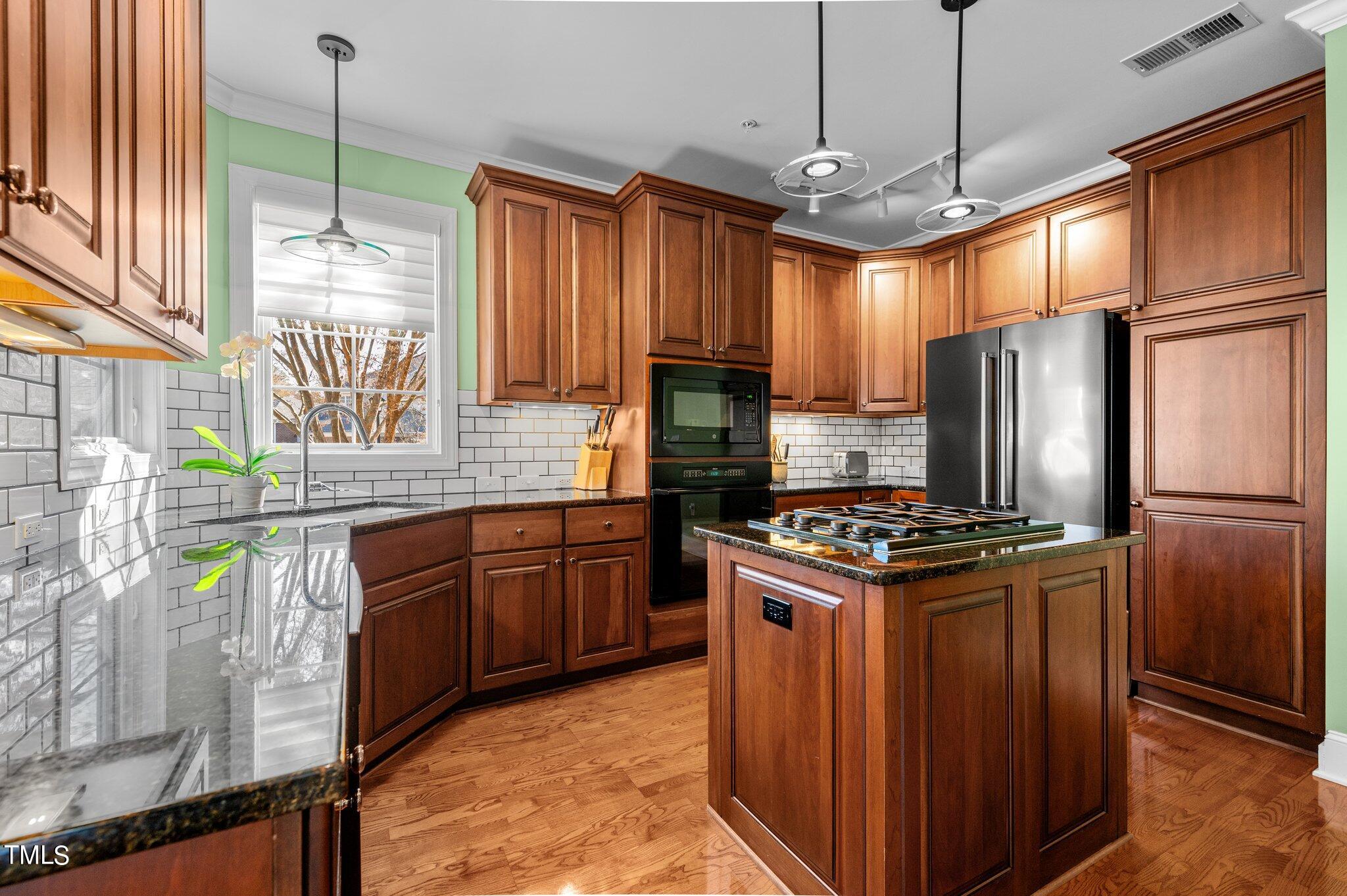 3700 Baron Cooper Pass, Unit 202 Raleigh, NC 27612 - Photo 23 of 49 a kitchen with stainless steel appliances granite countertop a stove a refrigerator and a sink with wooden cabinets