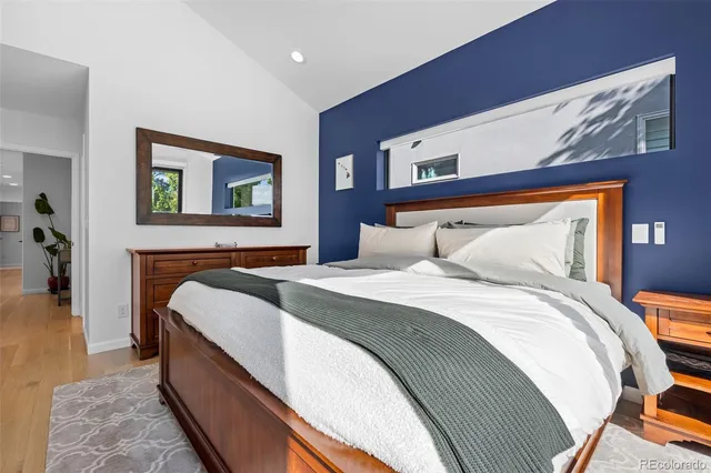 a bedroom with a bed painting on wall and a large window