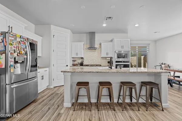 a kitchen with stainless steel appliances granite countertop a dining table chairs refrigerator and cabinets