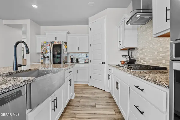 a large kitchen with stainless steel appliances granite countertop a lot of counter space and wooden floors
