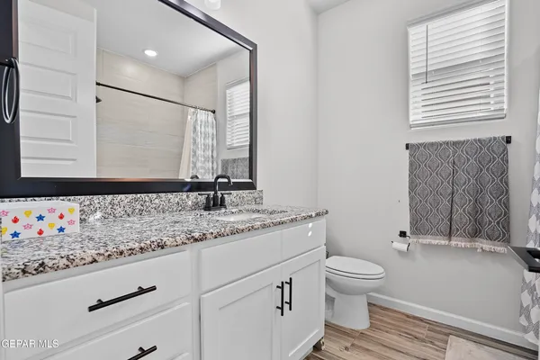a bathroom with a granite countertop sink toilet and mirror
