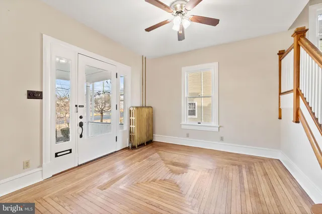 a view of an empty room with window and wooden floor