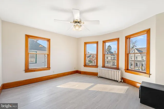 an empty room with a fan & a window