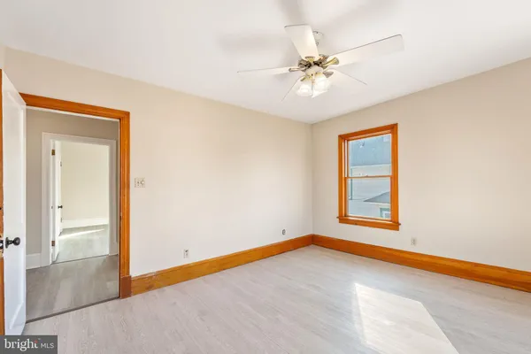an empty room with wooden floor ceiling fan and windows