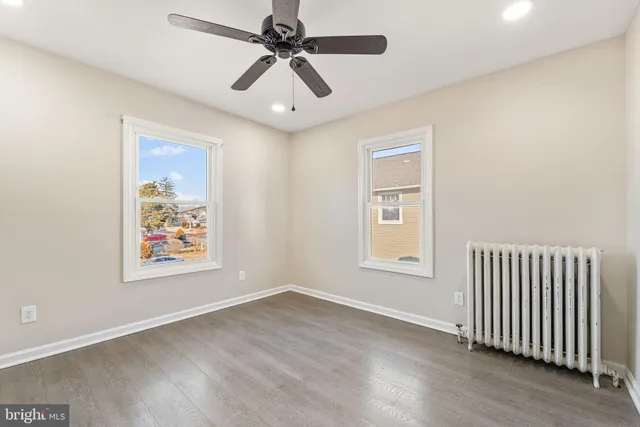 an empty room with wooden floor and ceiling fan