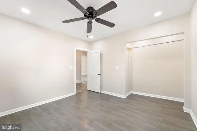 a view of empty room with wooden floor and ceiling fan