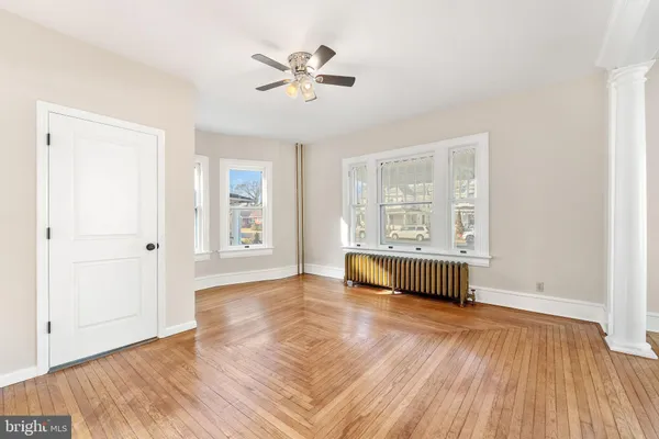 an empty room with wooden floor a ceiling fan and windows