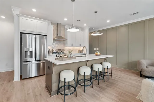 a kitchen with stainless steel appliances granite countertop a refrigerator a sink a stove a dining table and chairs with wooden floor