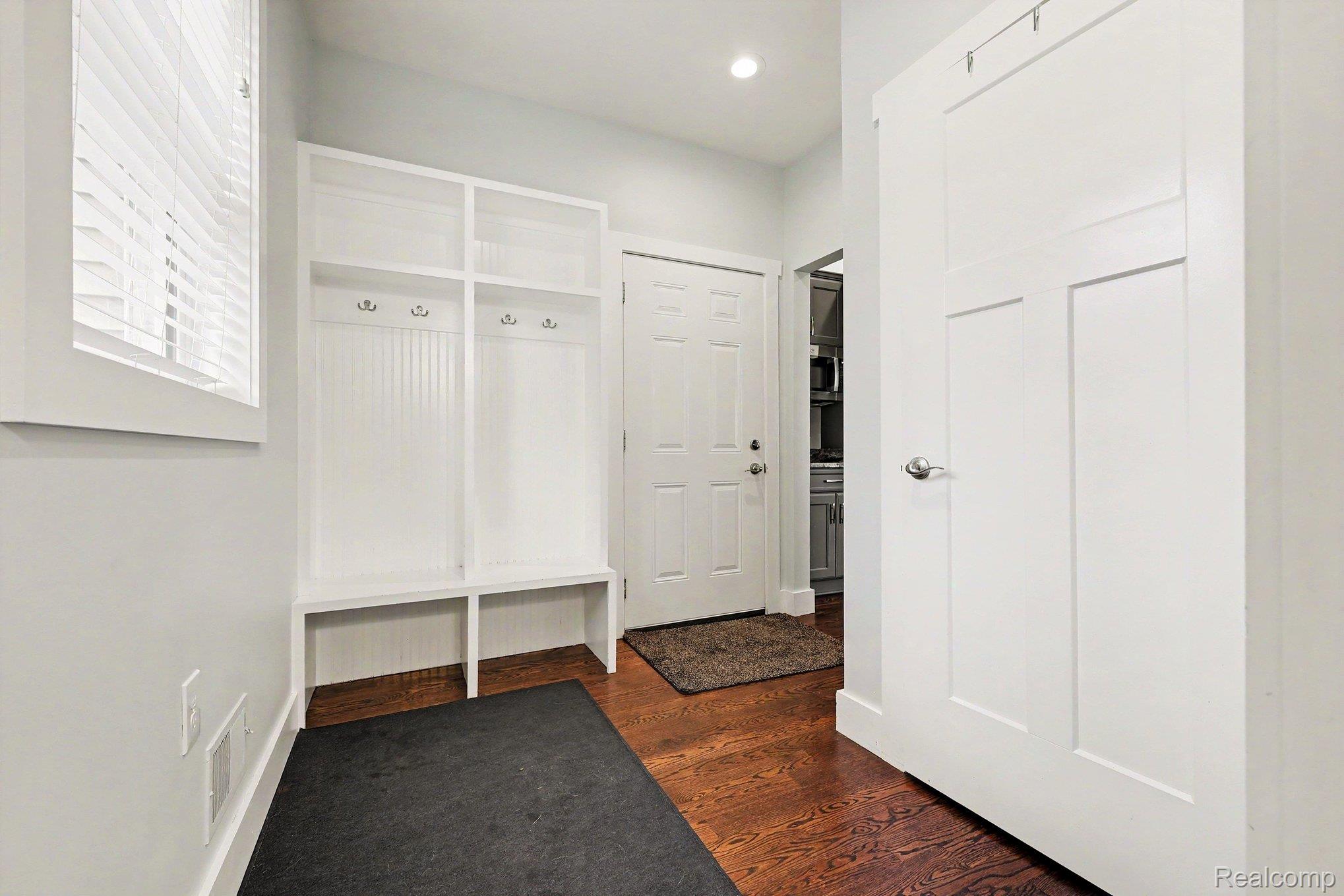 1660 Winthrop Road Bloomfield Hills, MI 48302 - Photo 26 of 38 Built-in white storage bench with upper shelving and coat hooks, wood-finish flooring, and white interior doors