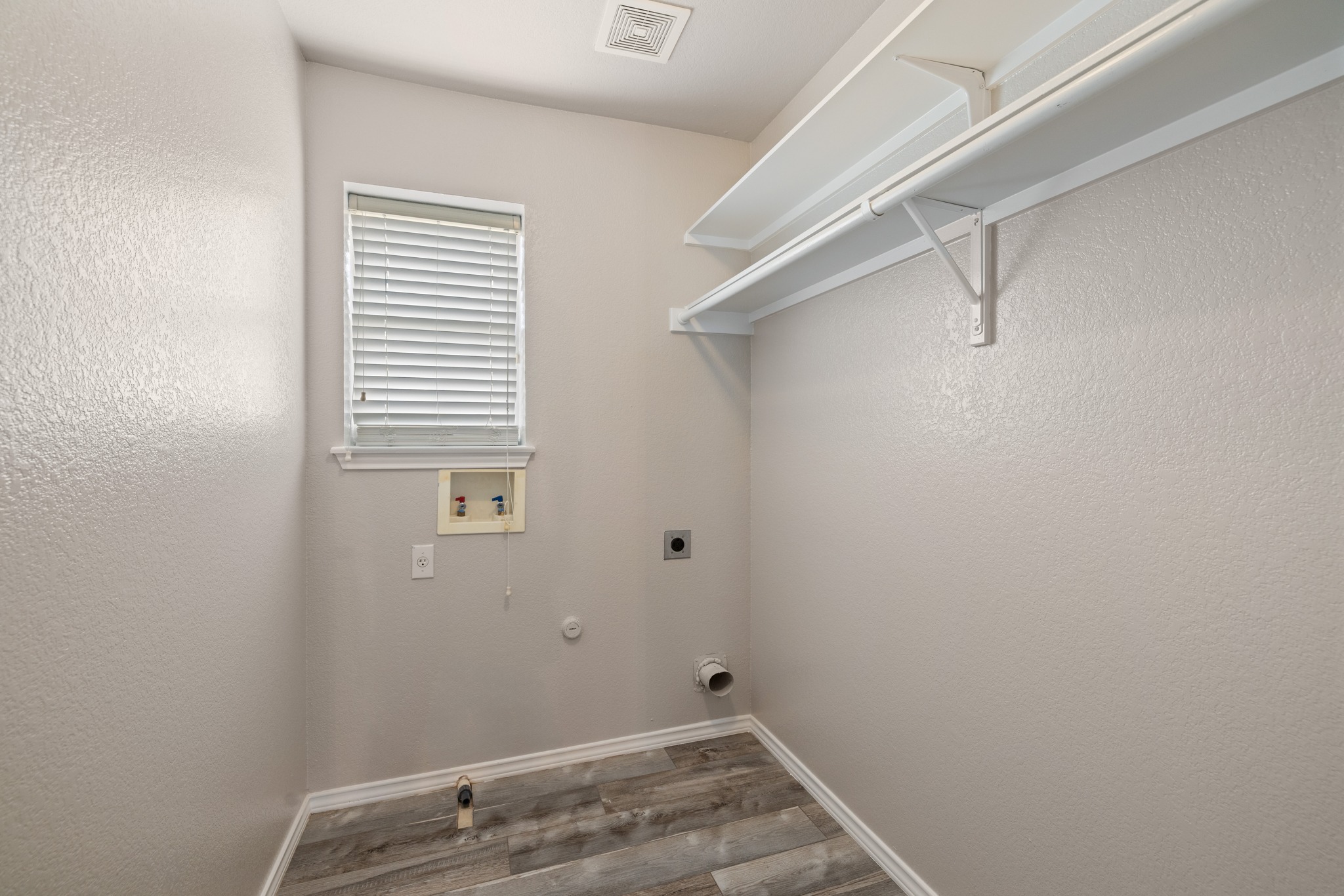 403 Red Hawk Drive Leander, TX 78641 - Photo 24 of 37 Dedicated utility space featuring wood-finish flooring, built-in shelving, and a window with blinds