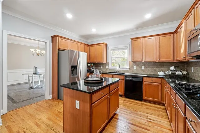 a kitchen with stainless steel appliances granite countertop a stove a sink dishwasher a refrigerator and cabinets with wooden floor