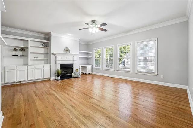 an empty room with wooden floor fireplace and windows