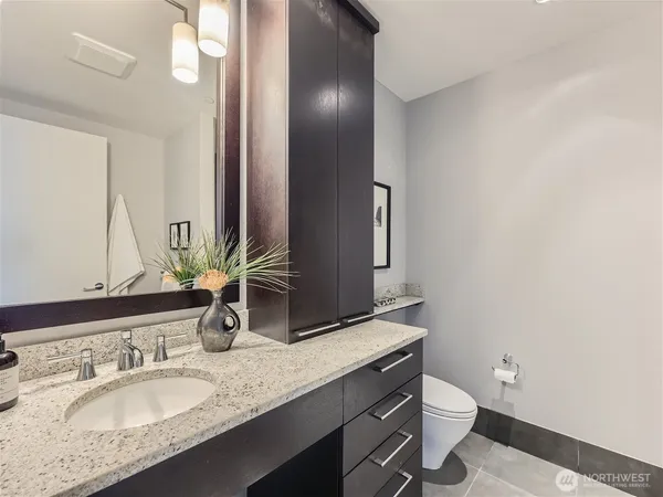 a bathroom with a granite countertop sink a toilet and a large mirror