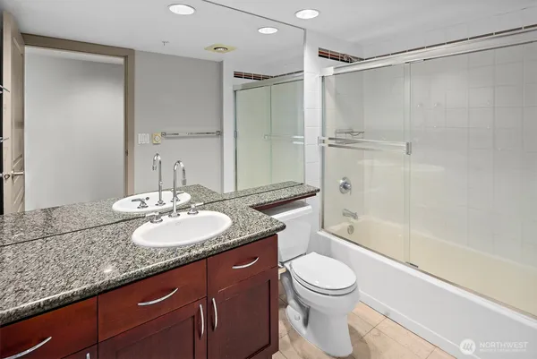a bathroom with a granite countertop sink toilet mirror and shower