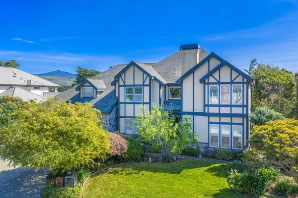 a view of a big house with plants and large trees