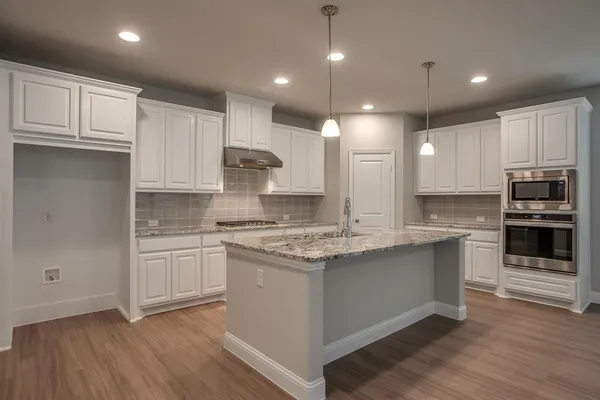 a kitchen with kitchen island granite countertop a stove sink and cabinets