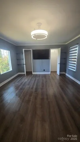 an empty room with wooden floor cabinet and windows