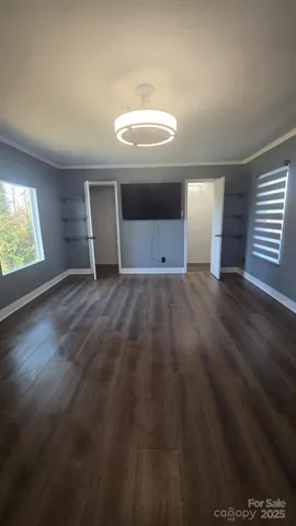 an empty room with wooden floor cabinet and windows