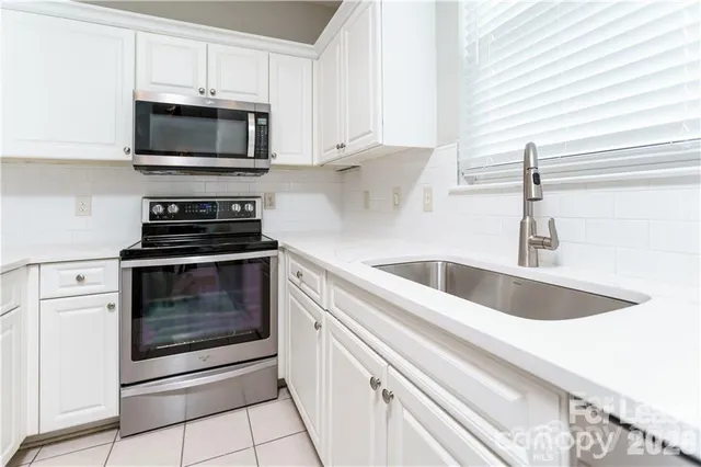 a kitchen with white cabinets and appliances