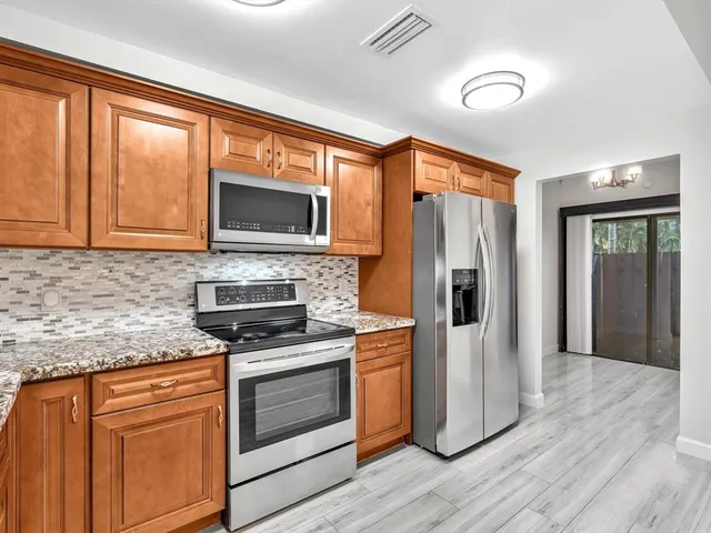 a kitchen with granite countertop a stove top oven microwave and refrigerator