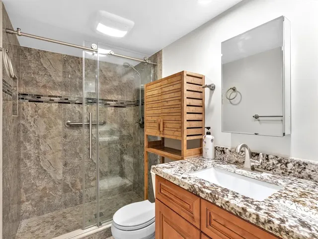 a bathroom with a granite countertop sink toilet and shower