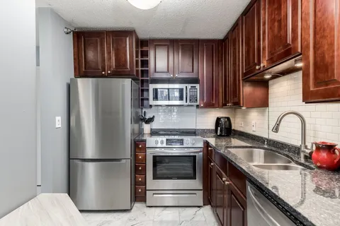 a kitchen with stainless steel appliances granite countertop a refrigerator stove a sink dishwasher and microwave oven