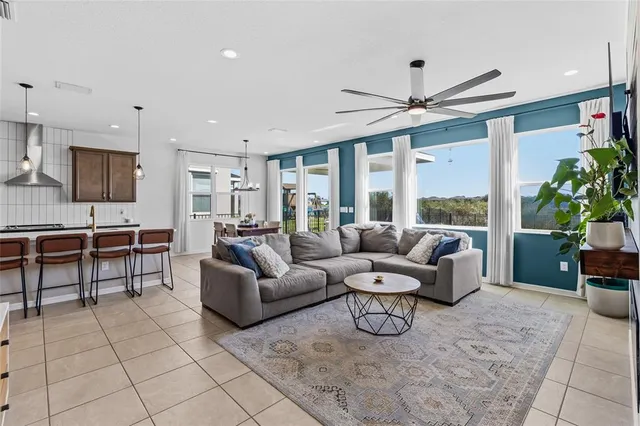 a living room with furniture ceiling fan and a large window